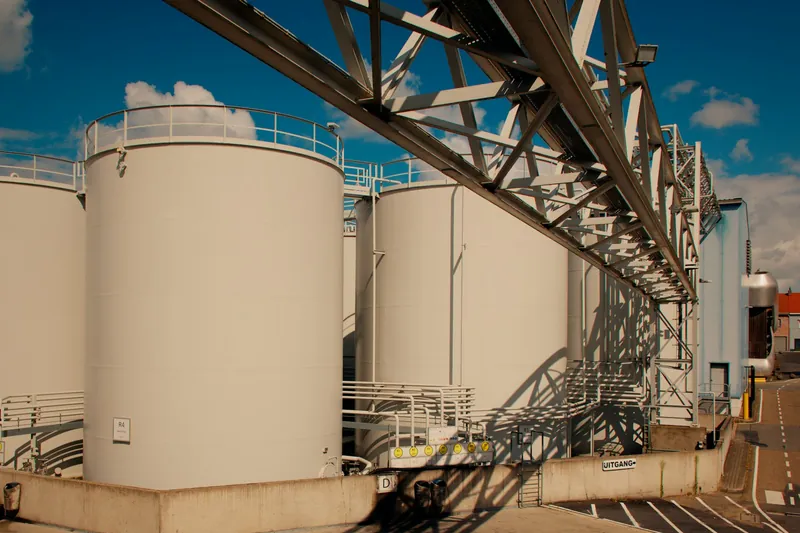 Witte opslagtanks met een stalen leidingbrug op een industrieterrein