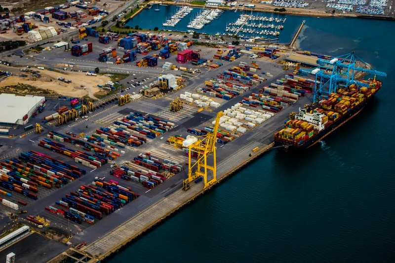Luchtfoto van een containerterminal met kranen aan de kade en een containerschip dat gelost wordt